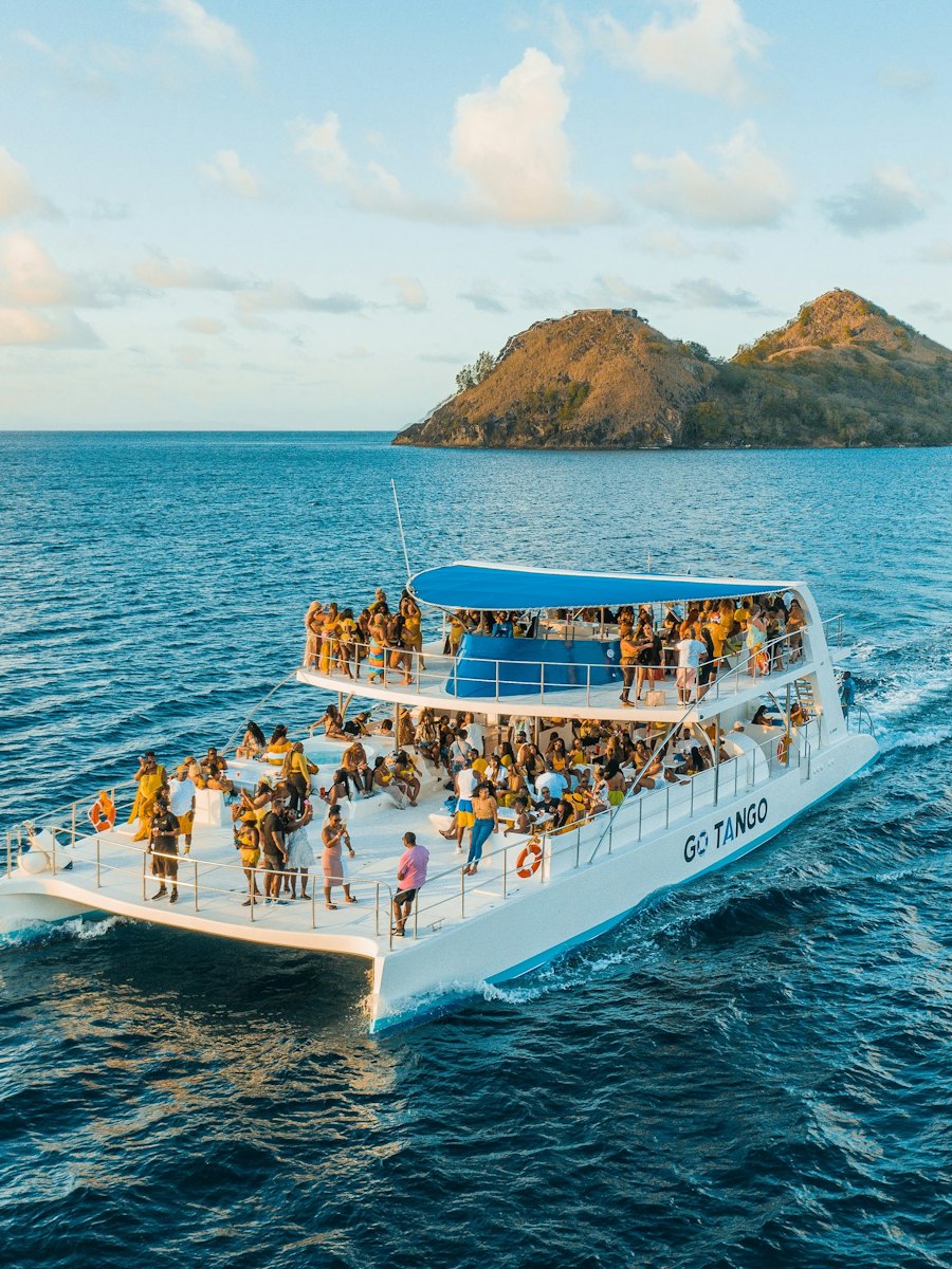 Large group celebrating aboard a catamaran near an island