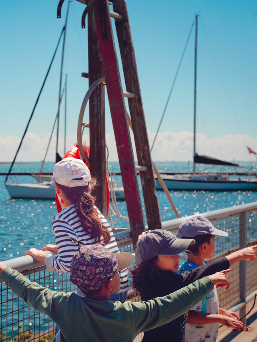 Children at a deck rail watching sailboats in the bay